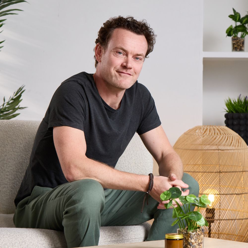 Aduna co-founder sitting on a couch in a modern living room.