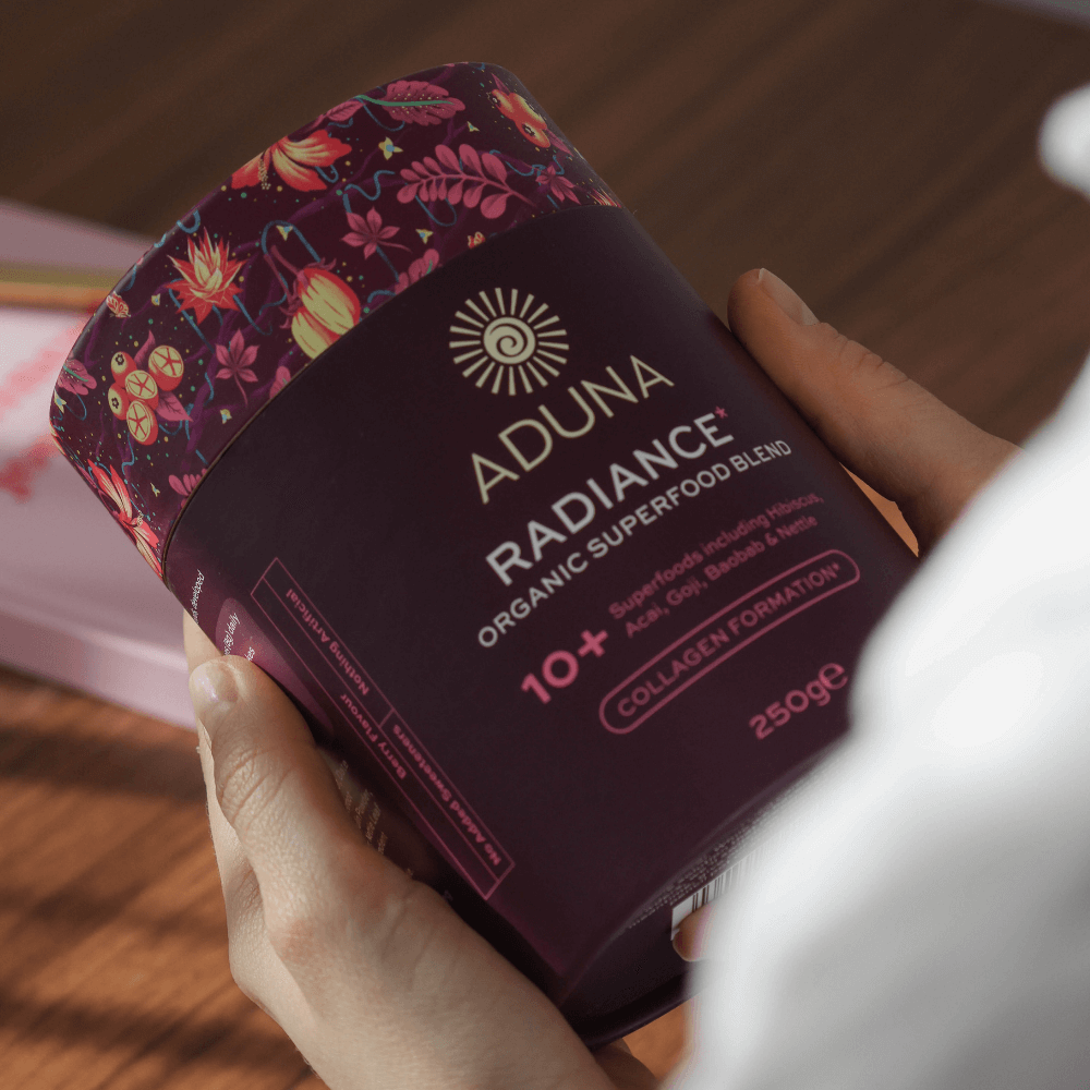Hands holding a package of Aduna Radiance Organic Superfood Blend