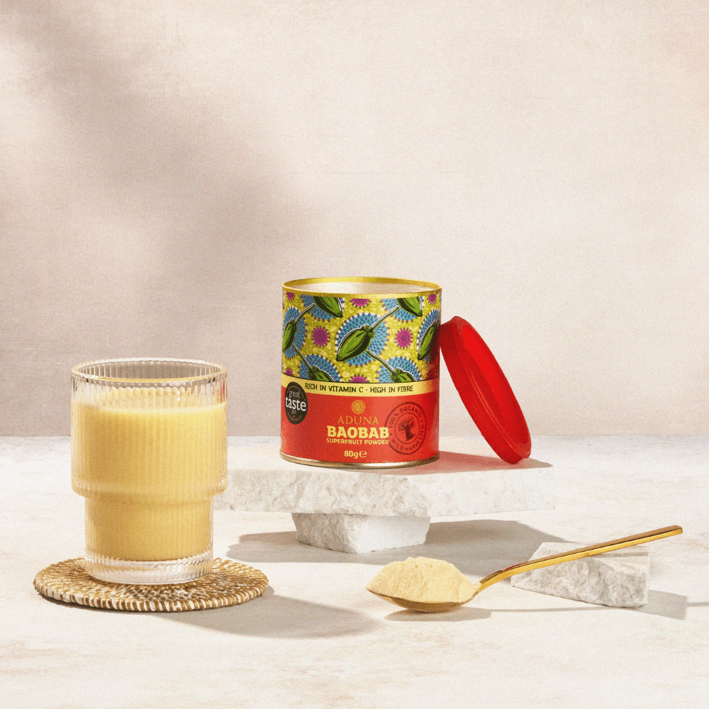 Aduna Baobab Superfruit Powder 80g packaging and a glass of liquid on a light surface