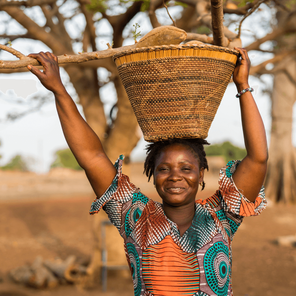 African woman smiling and holding a basket of baobab fruit above her head