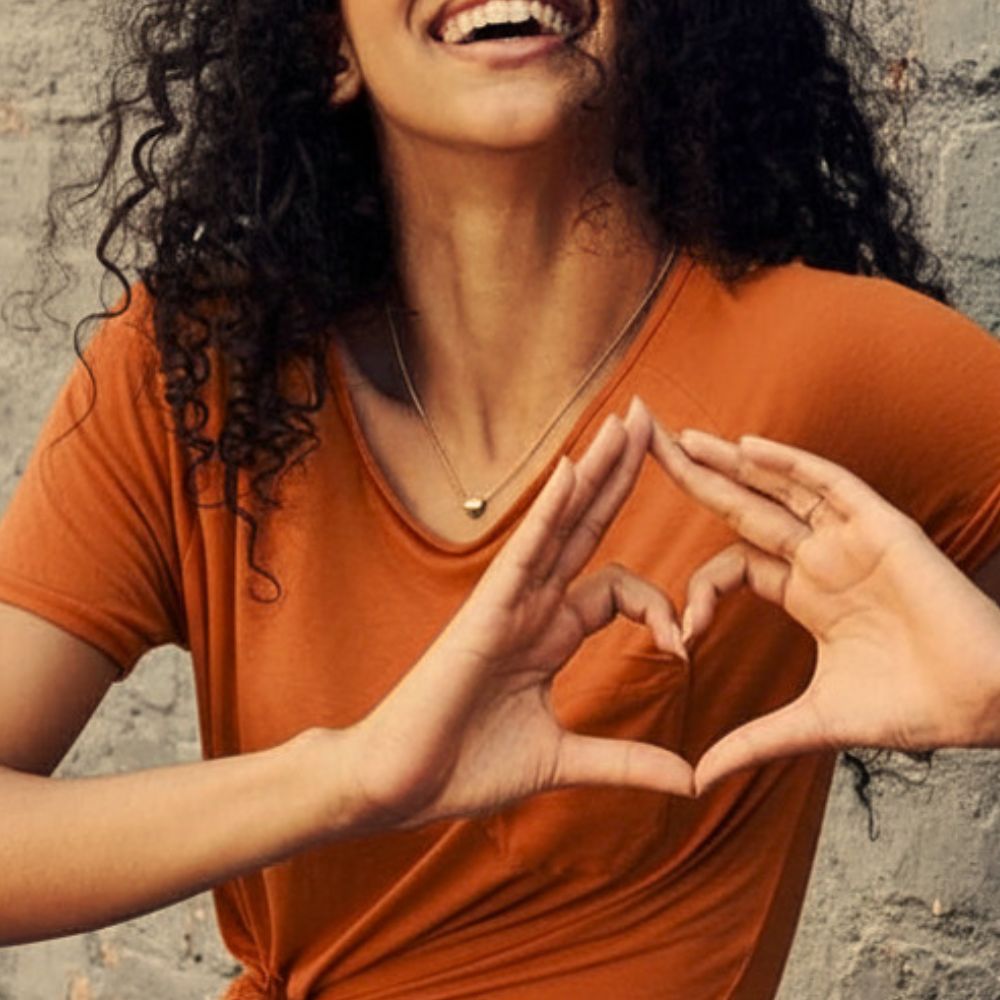 Woman making a heart shape with her hands to represent heart health.