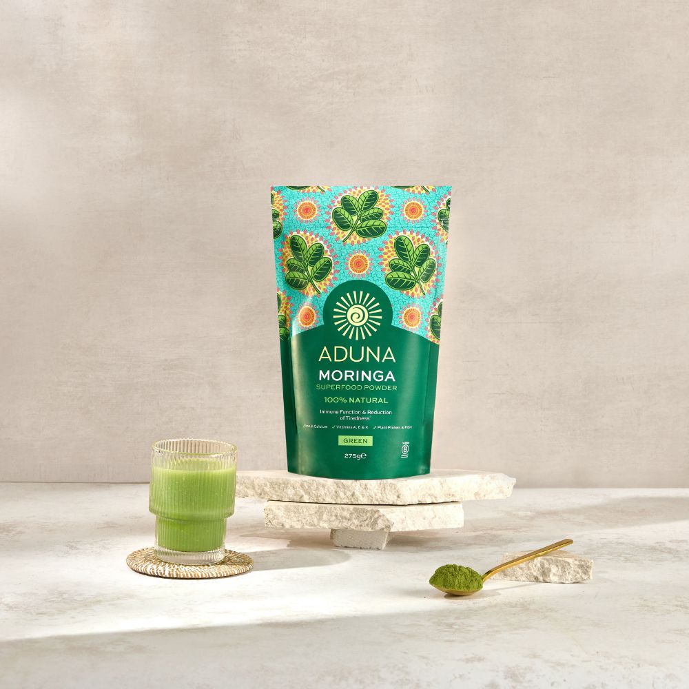 Aduna Moringa Powder Pouch, glass of green juice and a spoon of Moringa Powder