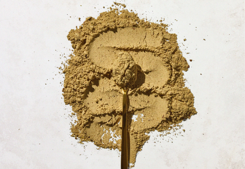 A teaspoon of superfood powder placed on top of a pile of superfood powder.
