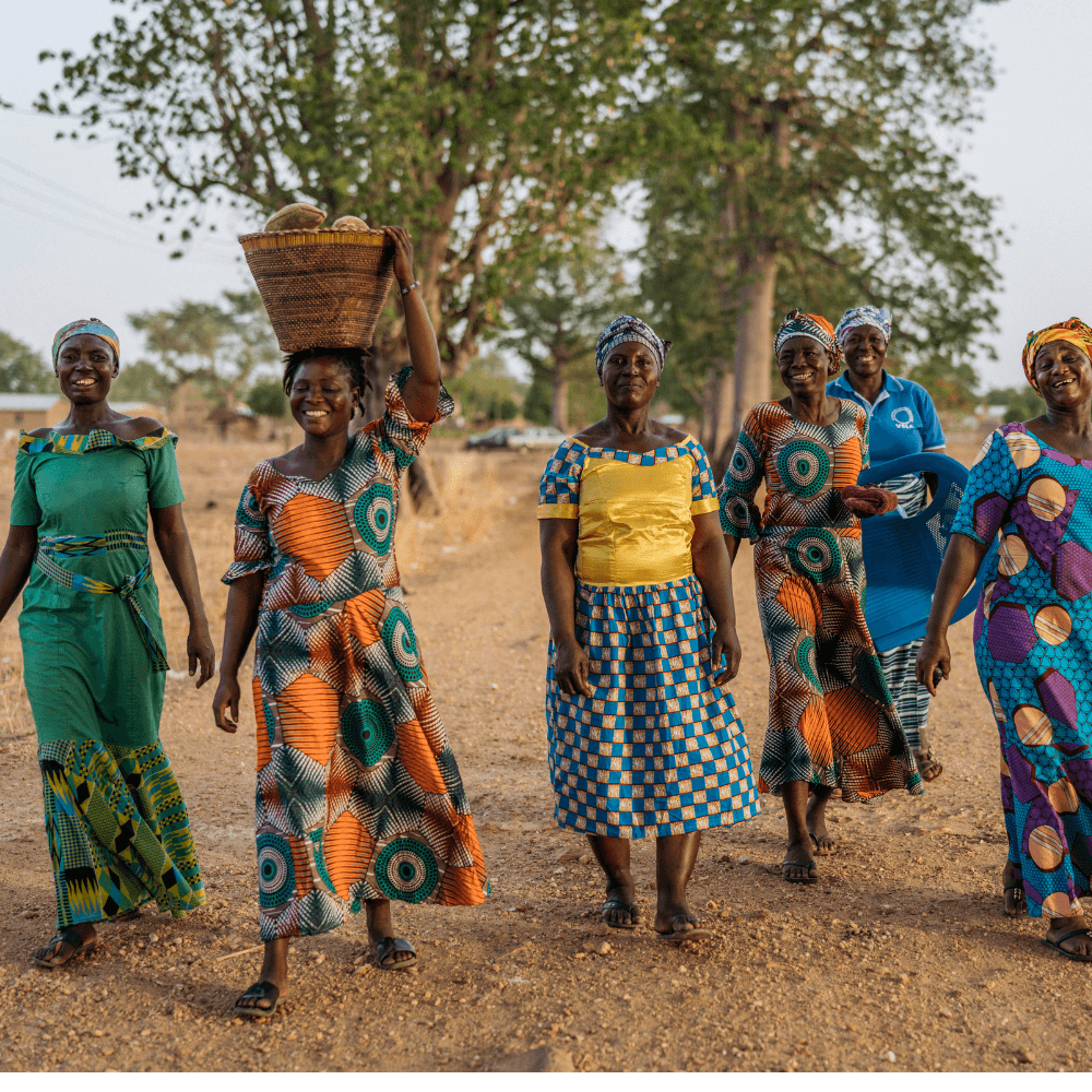 Group of African women in colourful traditional attire walking outdoors.