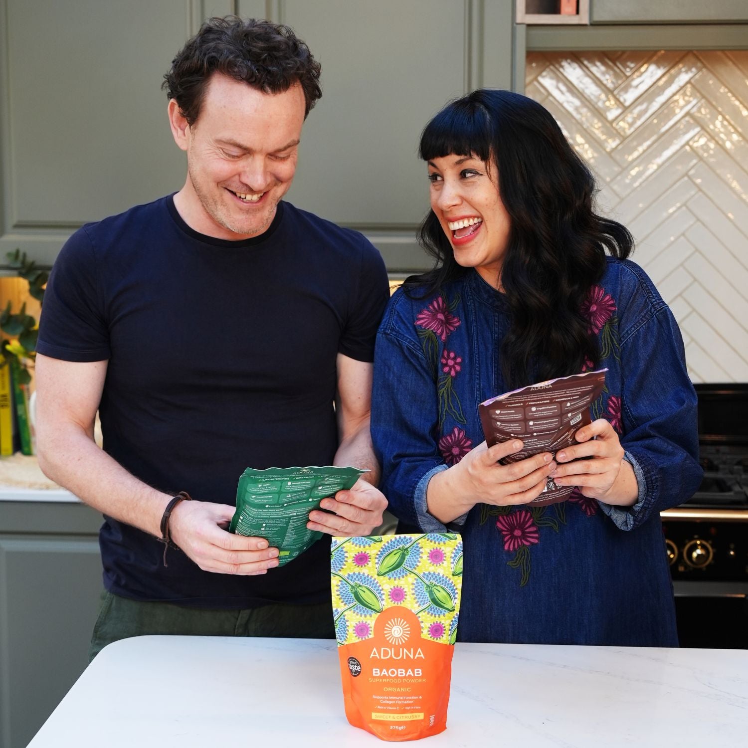 Aduna co-founder with Melissa Hemsley in a kitchen holding packages of Aduna products.